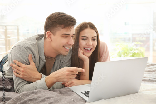 Happy young couple with laptop at home photo