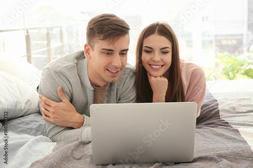Happy young couple with lap...