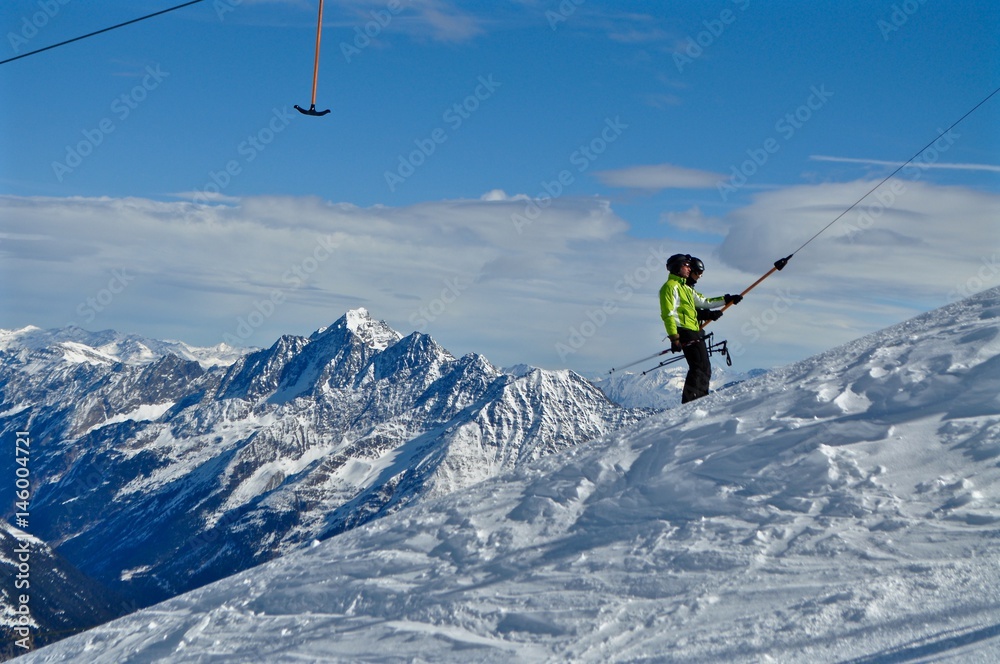 Tiroler Bergwelt im Schnee, am Stubaier Gletscher: zwei Skifahrer am Skilift / Schlepplift. Im Hintergrund die Schneeberge, Österreich
