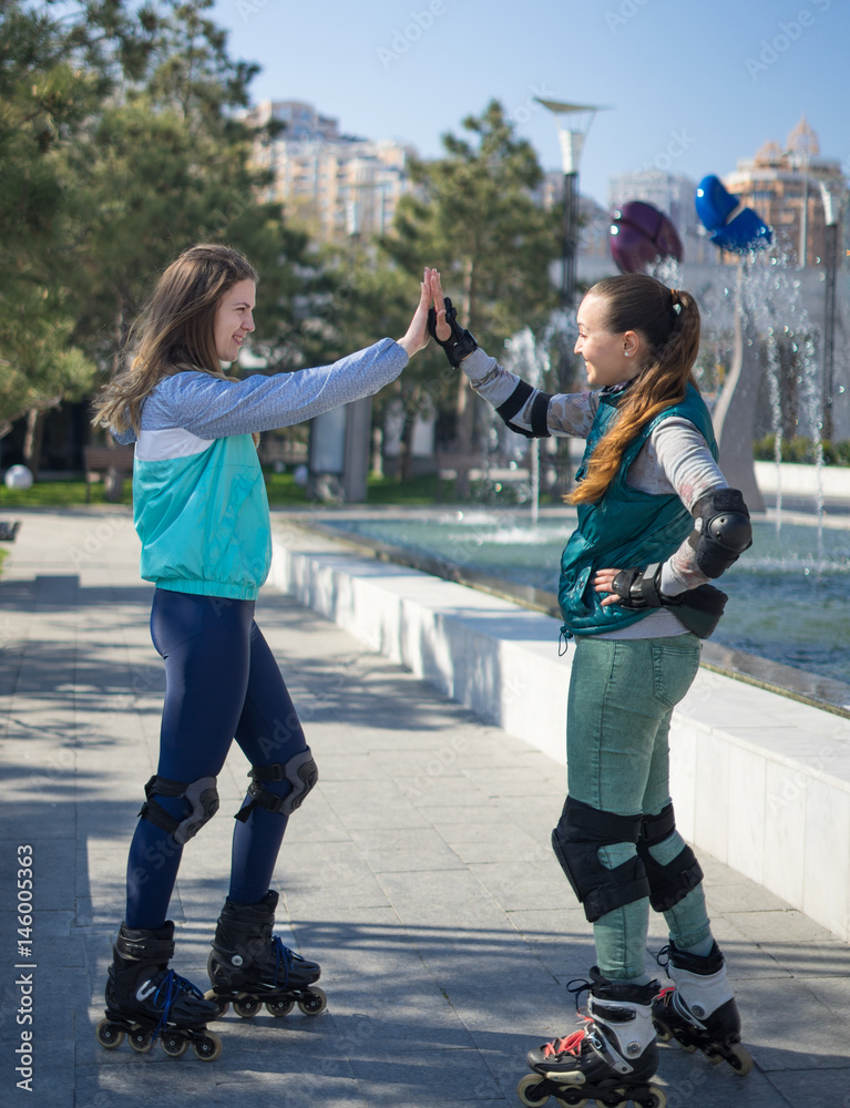 Two roller girls giving hive five in the park. Meeting of friends for roller  skating. They are smiling Stock Photo | Adobe Stock