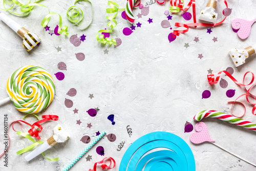 Colored party sweets and confetti on stone background top view mockup