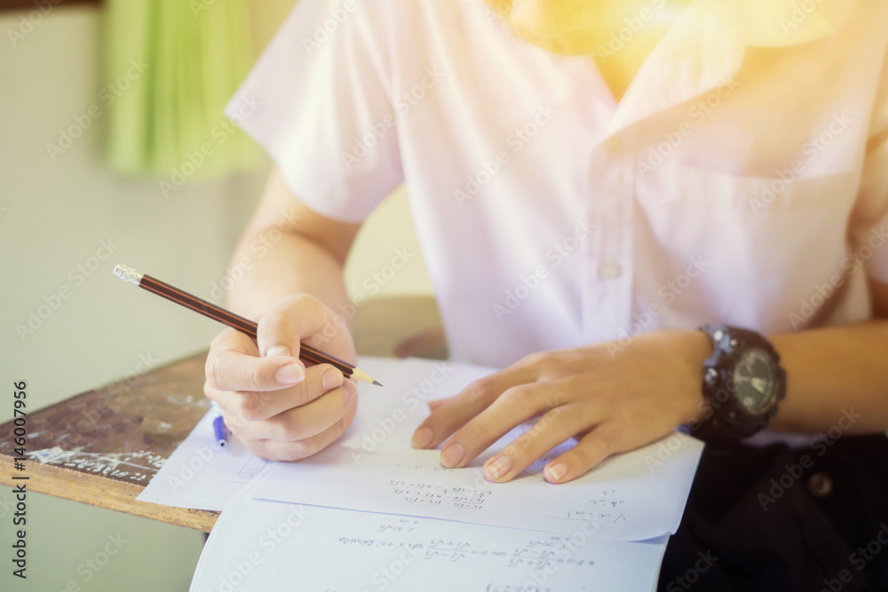 Student hand holding pencil writing doing examination with blurred abstract  background university boy in uniform attending exam classroom educational  school: college people in room vintage color Stock Photo | Adobe Stock