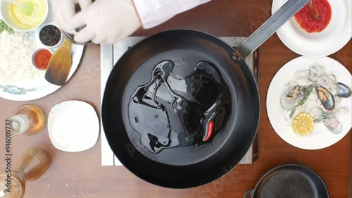 Olive oil poured into the frying pan from the bottle photo