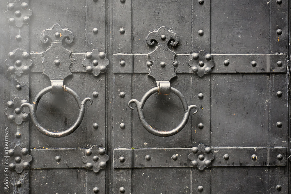Metal rusty round handle on black wooden door.