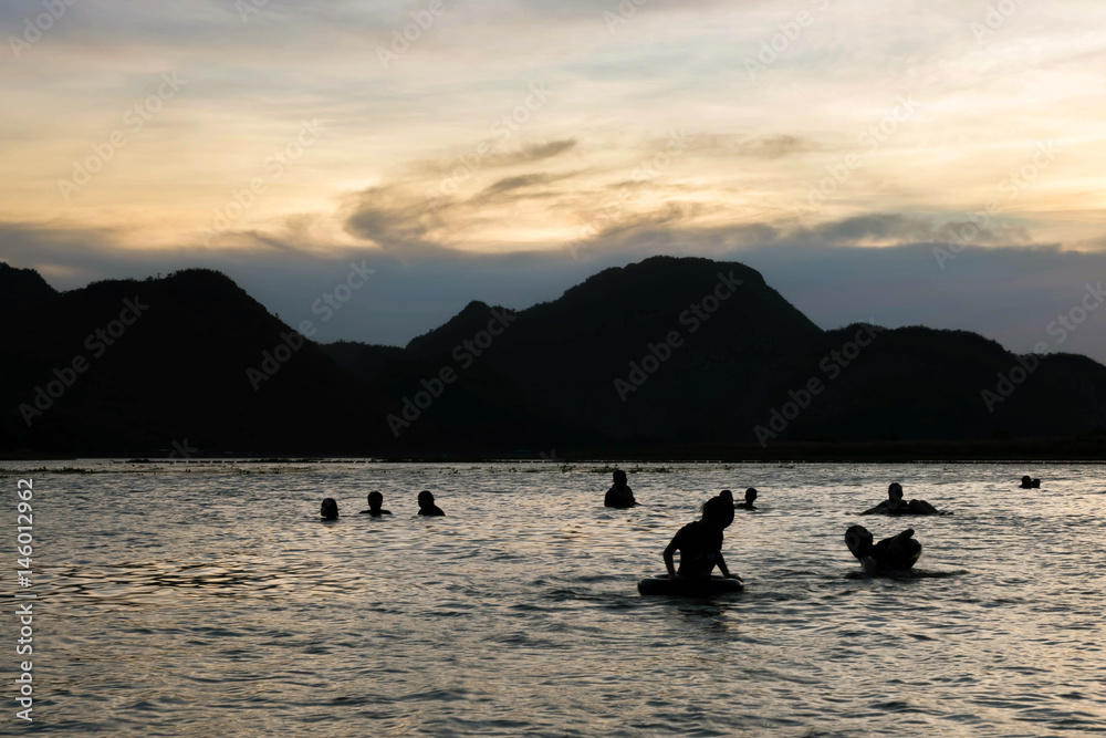 Silhouette , blurry , art tone of fresh water lake and mountain with people playing water on evening sky background