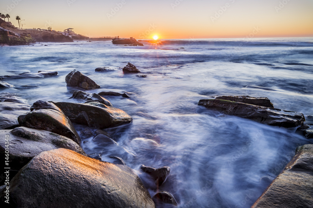 Obraz premium Sun setting over a rocky beach