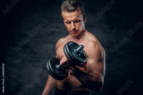 Shirtless athletic male doing biceps exercise with dumbbells.