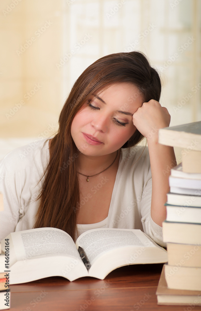 Portrait of clever student with open book reading it in college library falling asleep Portrait of clever student with open book reading it in college library falling asleep