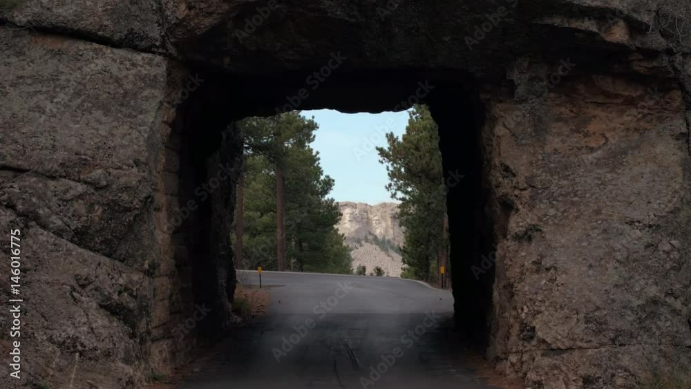 SLOW MOTION: Great vista point from the Narrow single lane tunnel in granite rock face revealing scenic view of the iconic Mount Rushmore monument in Black Hills, South Dakota. Four famous presidents