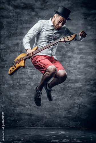 Funny bass player in a jump dressed in a cylinder hat.
