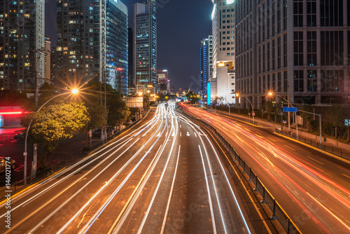 light trails on city street with cityscape at night in China.