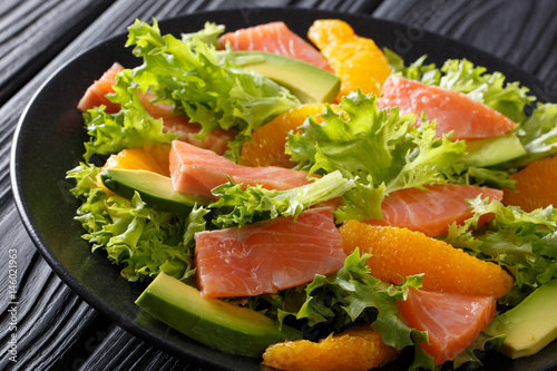 Delicious salad of salted salmon, oranges, avocado and frisee close-up. horizontal