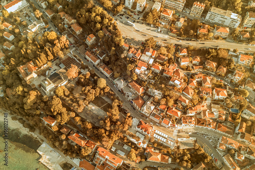 Top view of the city streets with red roofs of houses and highways. Toned