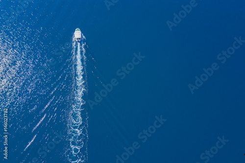 Top view of a white boat sailing to the blue sea