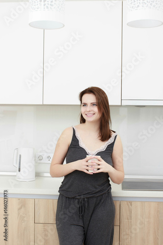 young woman With black hairdrinking coffee in the kitchen
