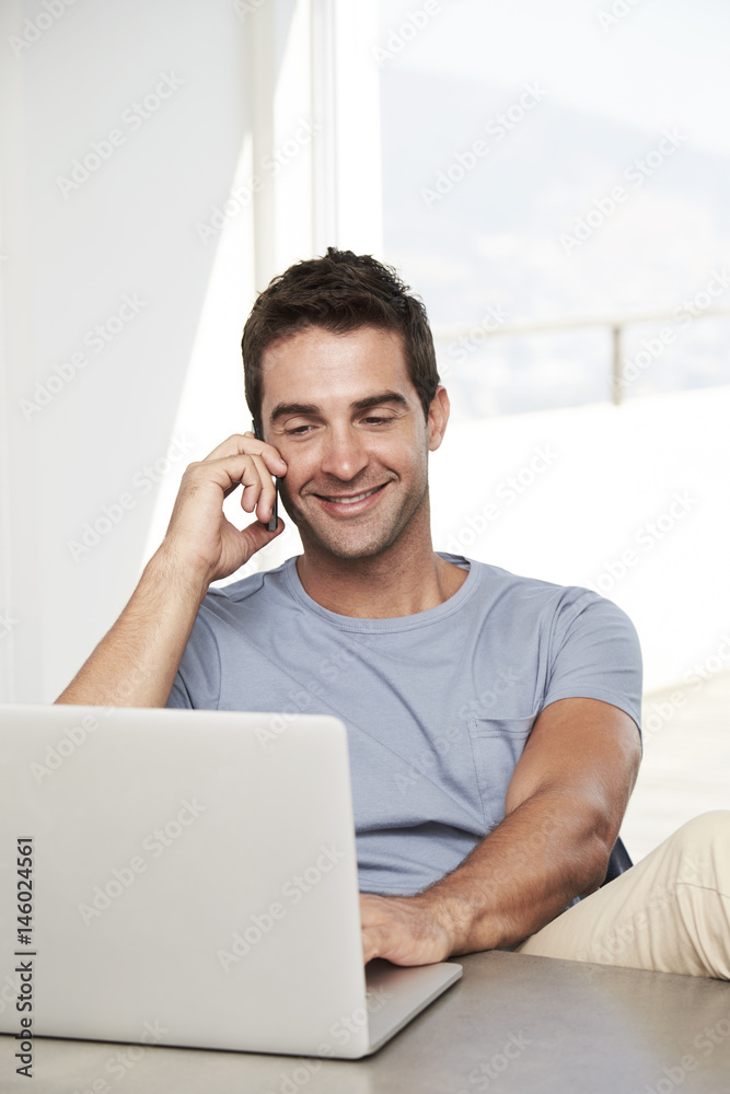 Smiling dude connected to phone and laptop Smiling dude connected to phone and laptop