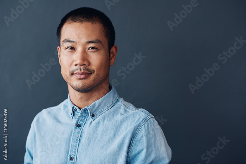 Confident and focused young Asian designer standing in an office