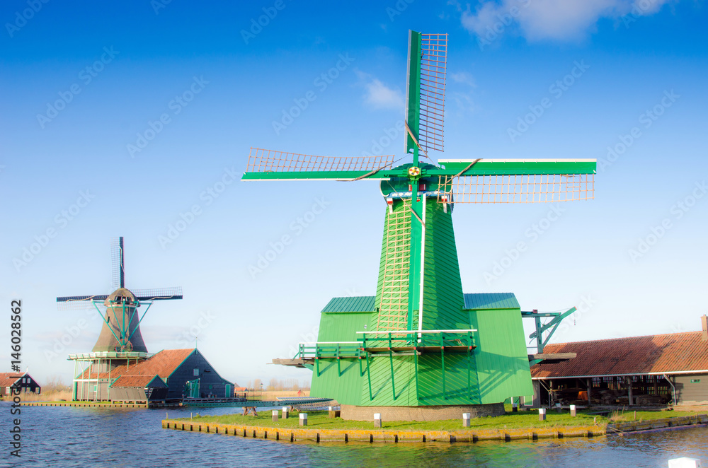 Scenic picture of the water and windmills in Zaanse Schans, Holland, Europe against the backdrop of a cloudy sky.