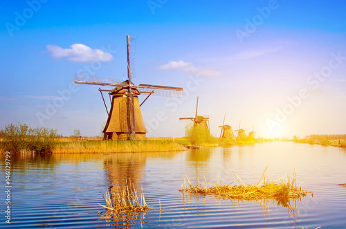 Unique beautiful landscape with windmills in Kinderdijk, Netherlands, Europe against a background of cloudy sky reflection in the water at sunset