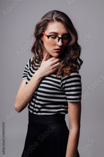 Smiling woman posing with glasses over the grey background