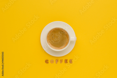 Top view of cup of fresh hot coffee and word coffee isolated on yellow