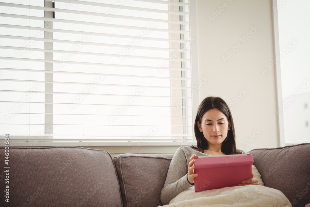 Woman using tablet while sitting on sofa Woman using tablet while sitting on sofa