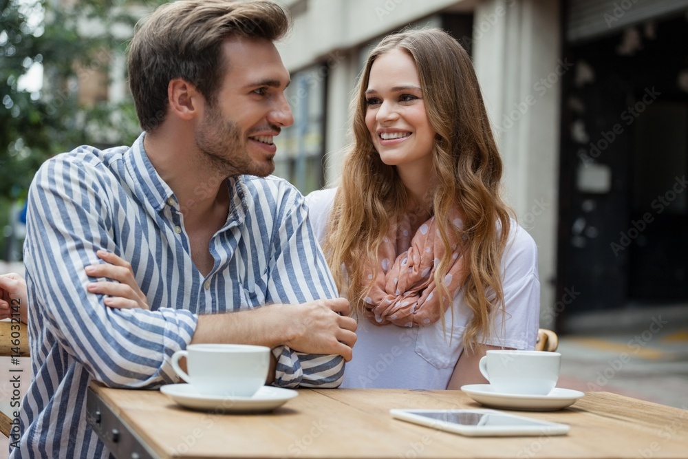 Couple sitting by table at sidewalk cafe