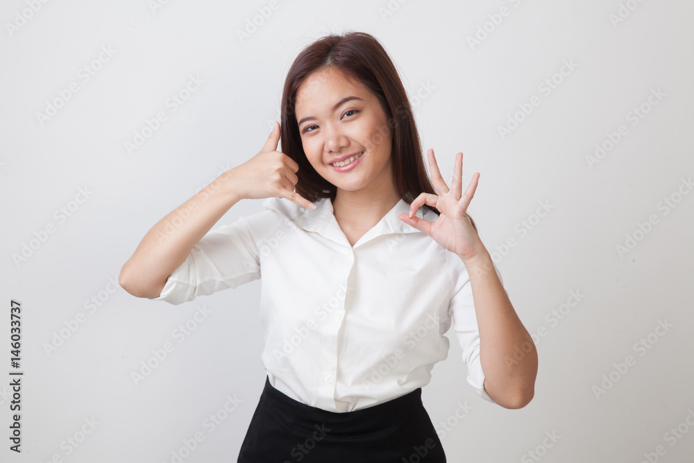 Young Asian woman show with phone gesture and OK sign. Young Asian woman show with phone gesture and OK sign.