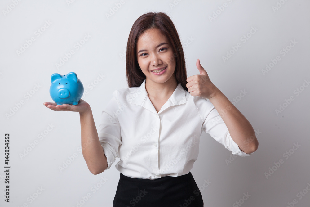 Asian woman thumbs up with pig coin bank. Asian woman thumbs up with pig coin bank.