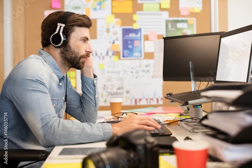 Businessman wearing headphones while working in creative office photo