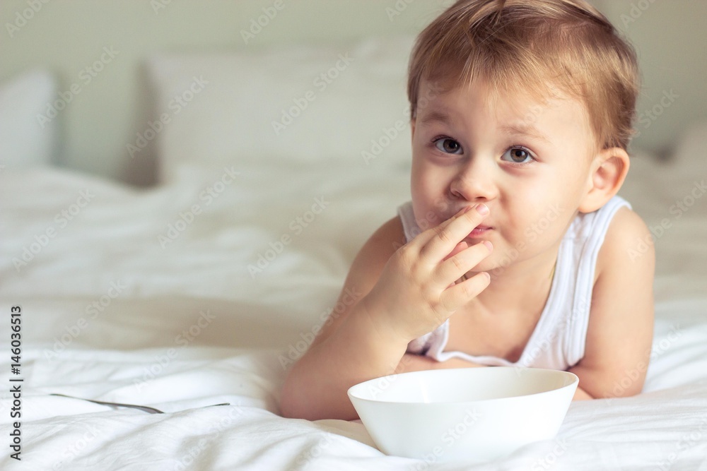 Little cute boy having breakfast in bed. Boy playing in bed. Breakfast in bed. Little cute boy having breakfast in bed. Boy playing in bed. Breakfast in bed.