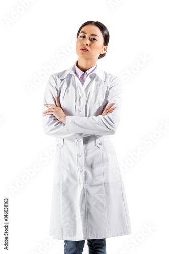 asian serious female doctor standing in white coat isolated on white
