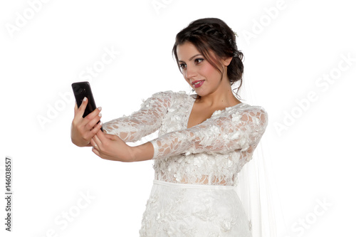 The bride takes a selfie on a white background