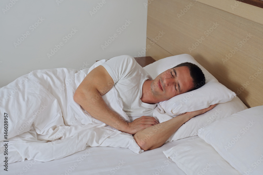 Young handsome man sleeping comfortably in bed.