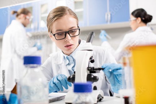 Focused young scientist working with microscope in research laboratory