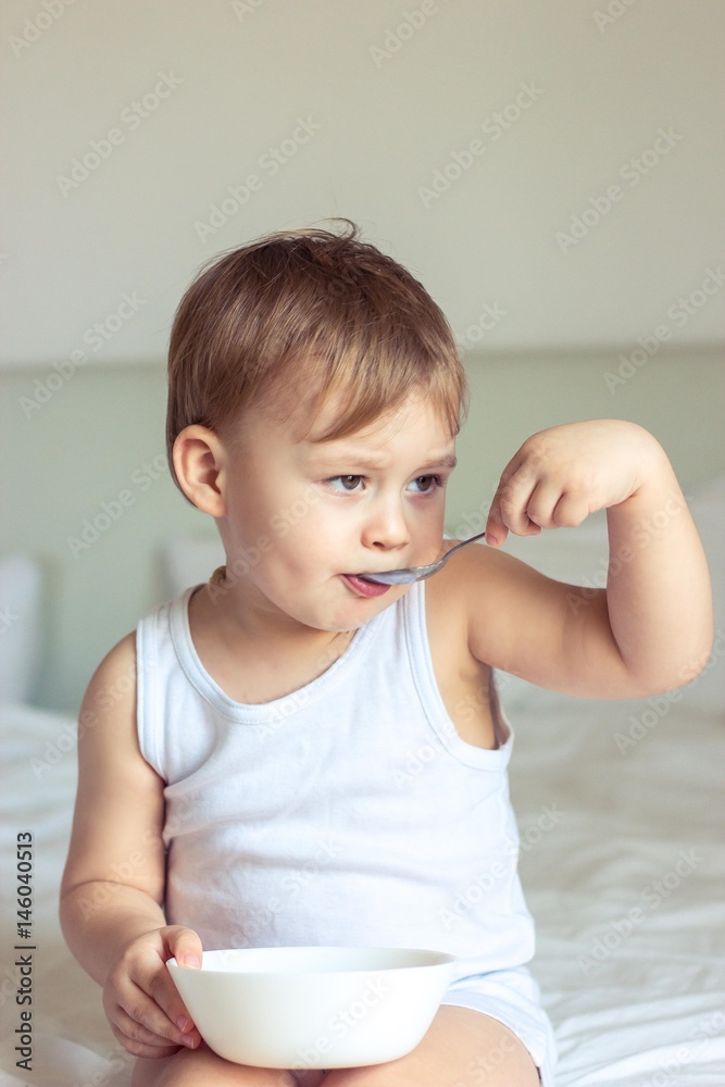 Little cute boy having breakfast in bed. Boy playing in bed. Breakfast in bed. Little cute boy having breakfast in bed. Boy playing in bed. Breakfast in bed.