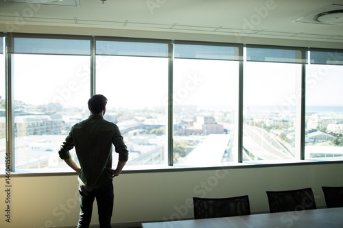 Rear view pf businessman looking through window at workplace