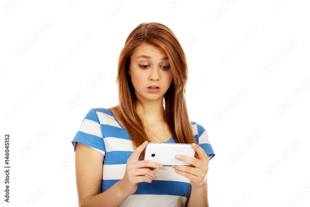 Teenage shocked woman reading a message on mobile phone Teenage shocked woman reading a message on mobile phone