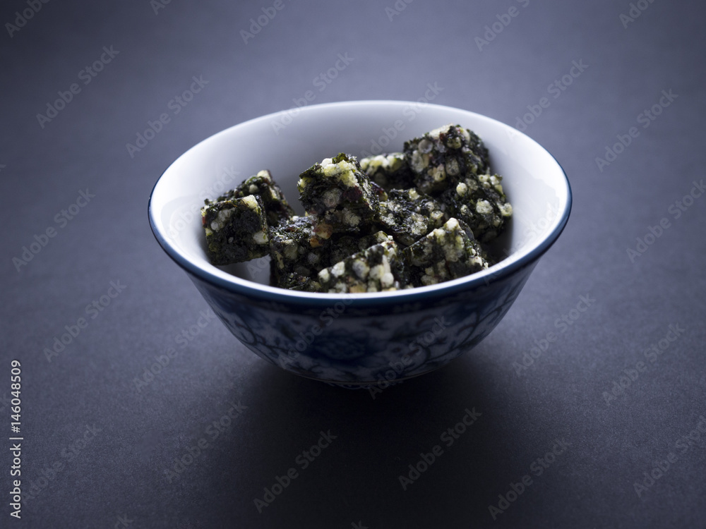 Seaweed snacks on cubes placed in Chinese bowl isolated on black background Seaweed snacks on cubes placed in Chinese bowl isolated on black background