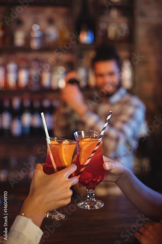 Hands of women toasting their cocktail drinks at counter