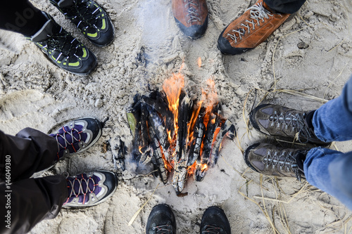 A groupof friends standing around a fire on a beach. photo