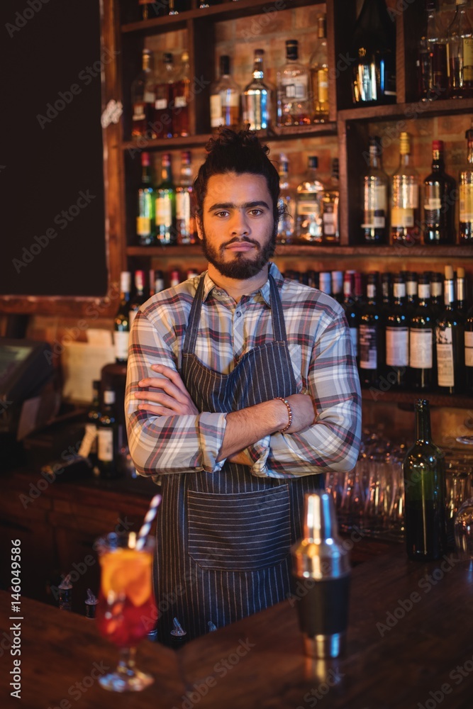 Portrait of waiter standing with arms crossed at counter