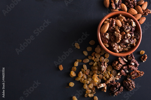 Nuts and raisins at black background. Healthy source of fat for vegans and vegetarians