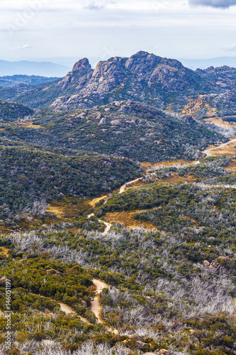 Winding dirt road and rugged cliffs at Mount Buffalo National Park, Victoria, Australia. Vertical image