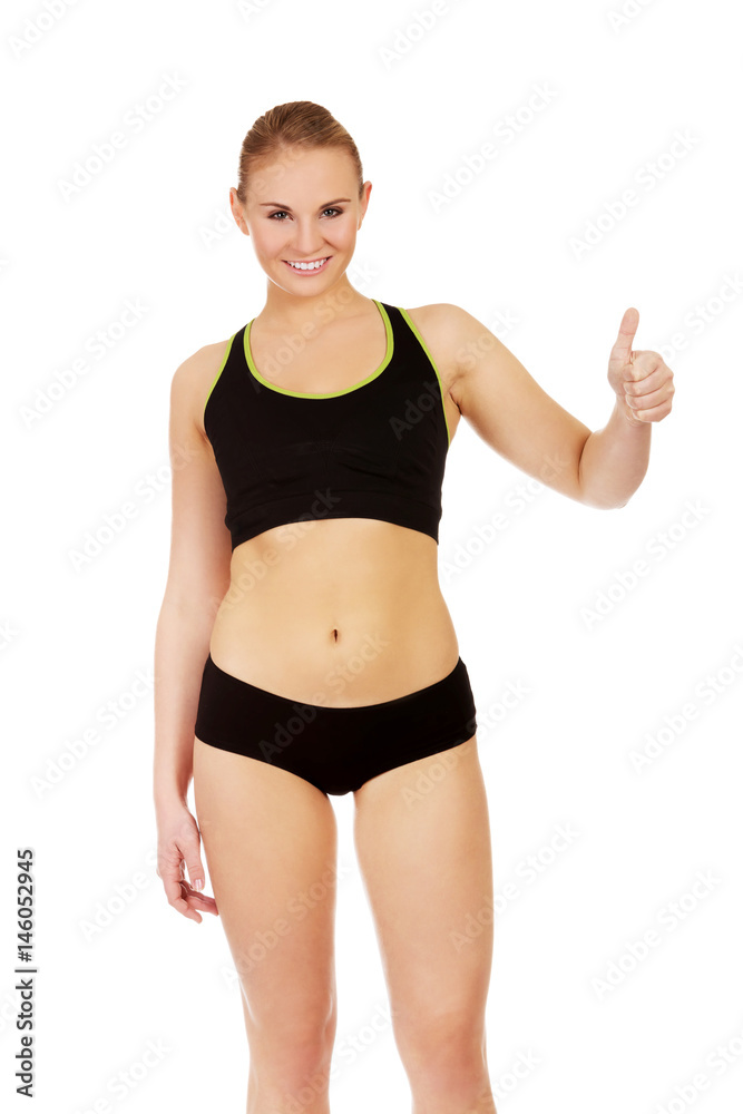 Young athletic woman showing thumb up