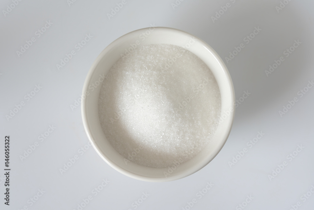 White granulated sugar in a white bowl. Unhealthy food concept.