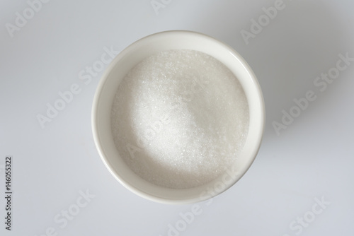 White granulated sugar in a white bowl. Unhealthy food concept.