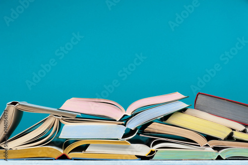 Open hardback colorful books on blue background. Back to school. Copy space for text. Education business concept.