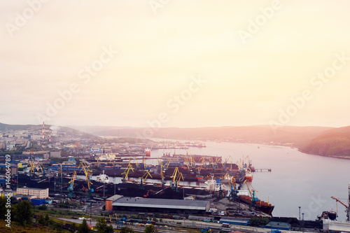 Embankment along with the river port, the crane unloads the coal from the box and loads it into the truck. Murmansk, Russia.Concept logistics, transportation, transport.