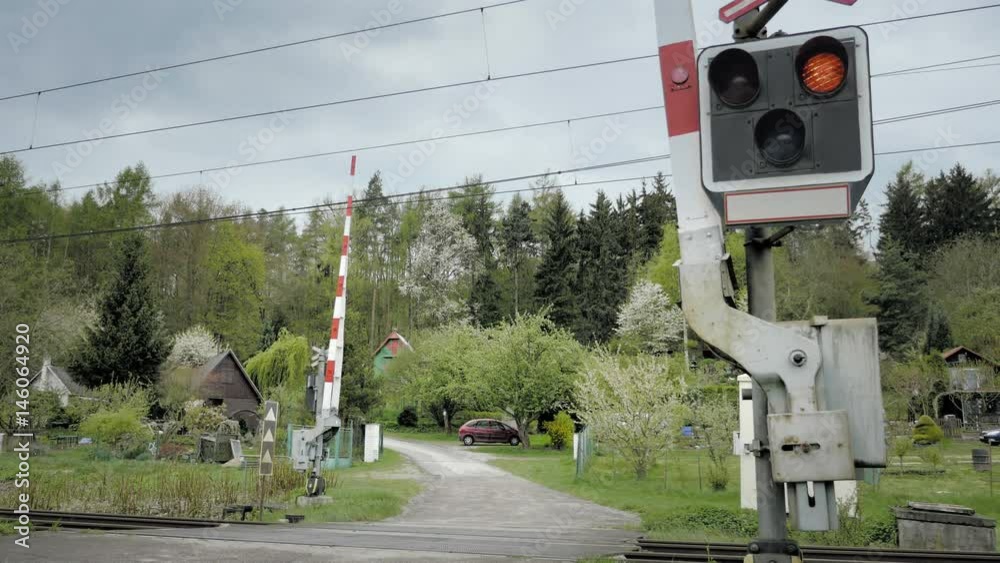Railroad crossing with railway gate that close. Level crossing occurs where railway barrier line is intersected by road or path on one level. Type of at-grade intersection. Static day stabilized shot.